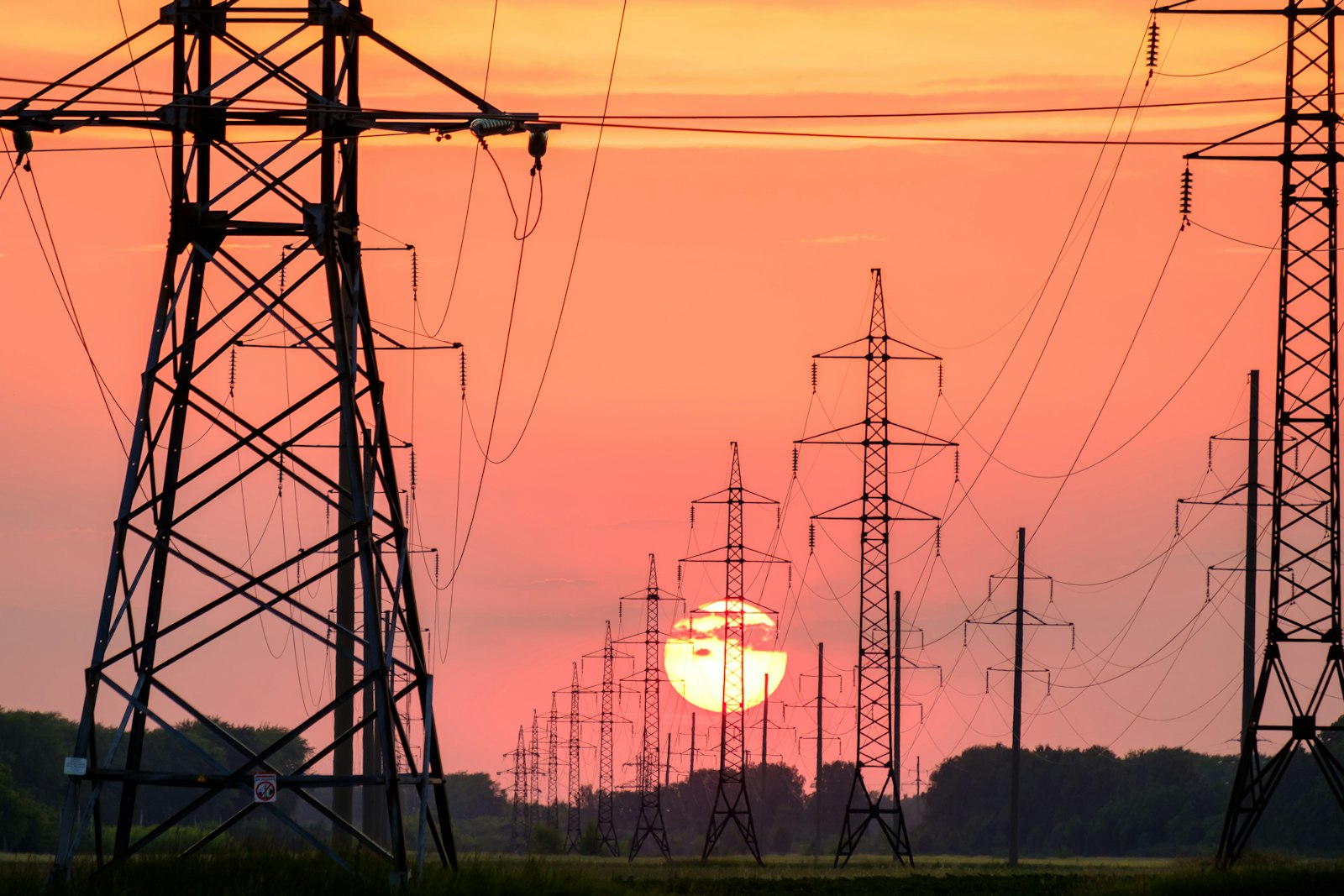 Electricity pylons silhouetted against a sunset
