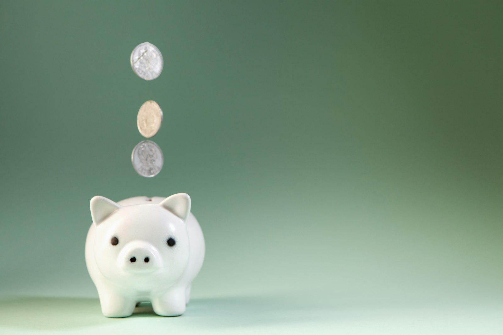 Coins dropping into a piggy bank