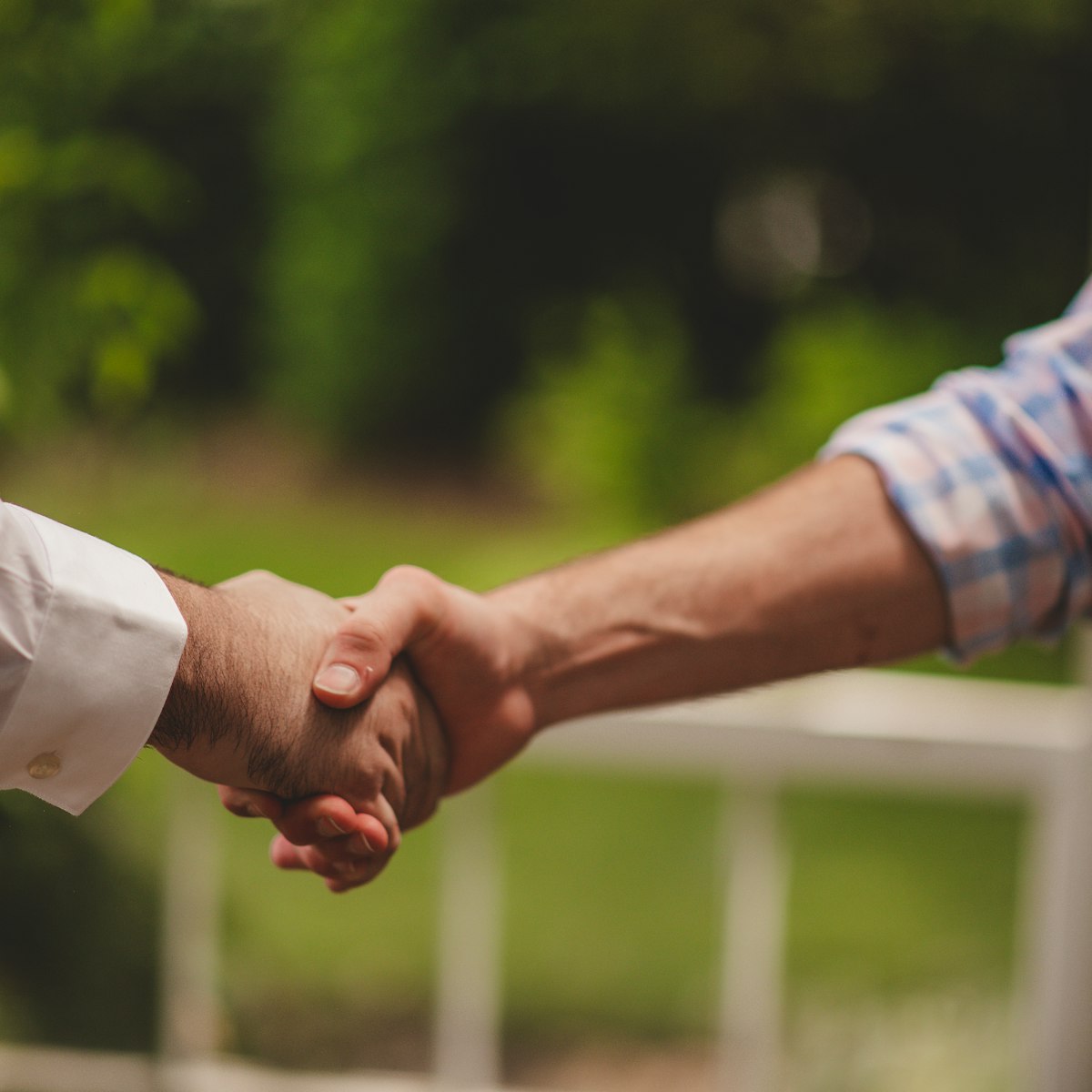 Two people shaking hands outside a home